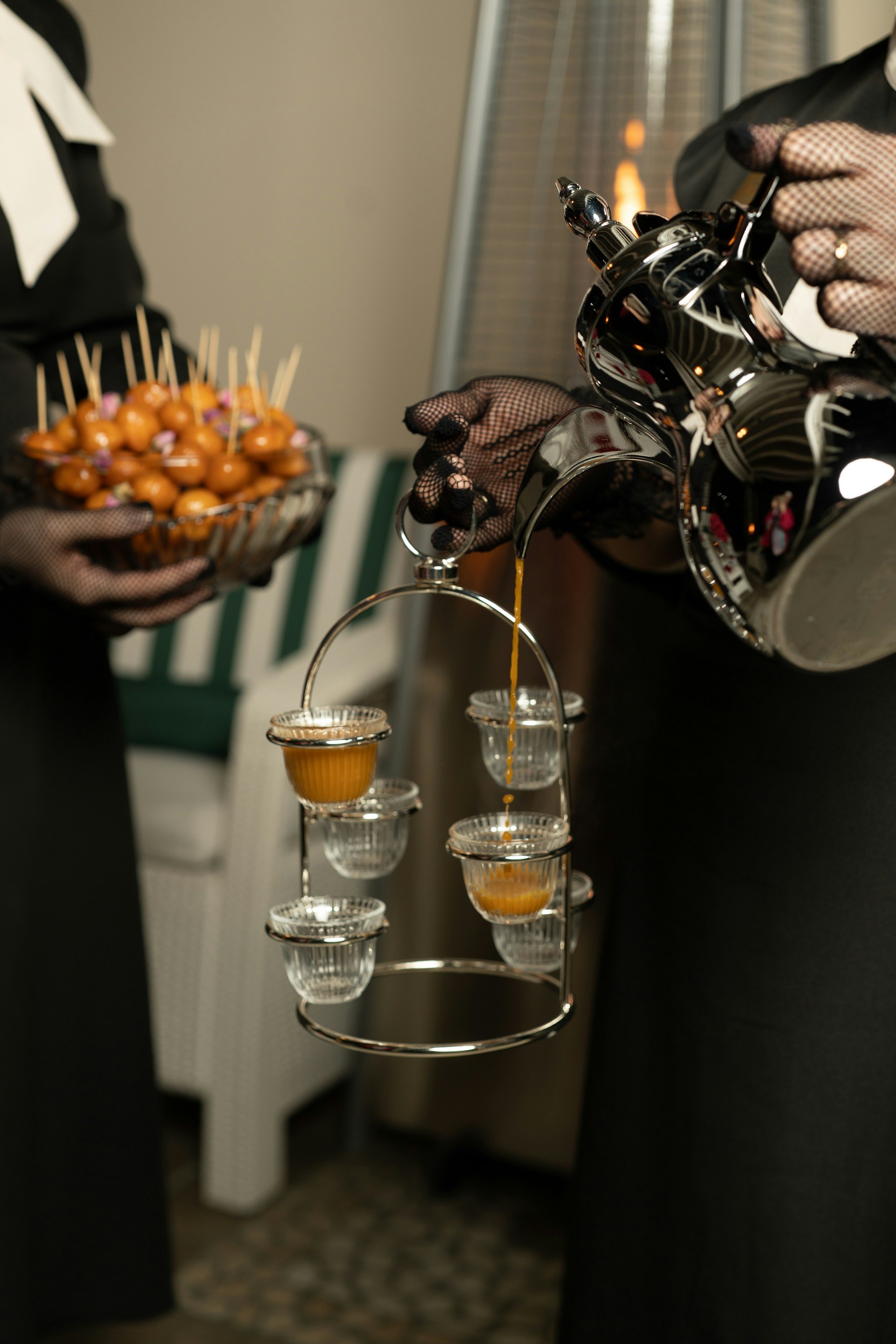 Gahwa poured from a silver dallah into small glass cups, with a dish of luqaimat